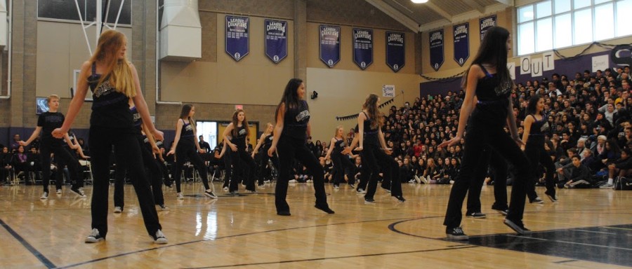 Sequoia dance team performs at the Winter rally in Gym 1 with the sport banners shown in the background.